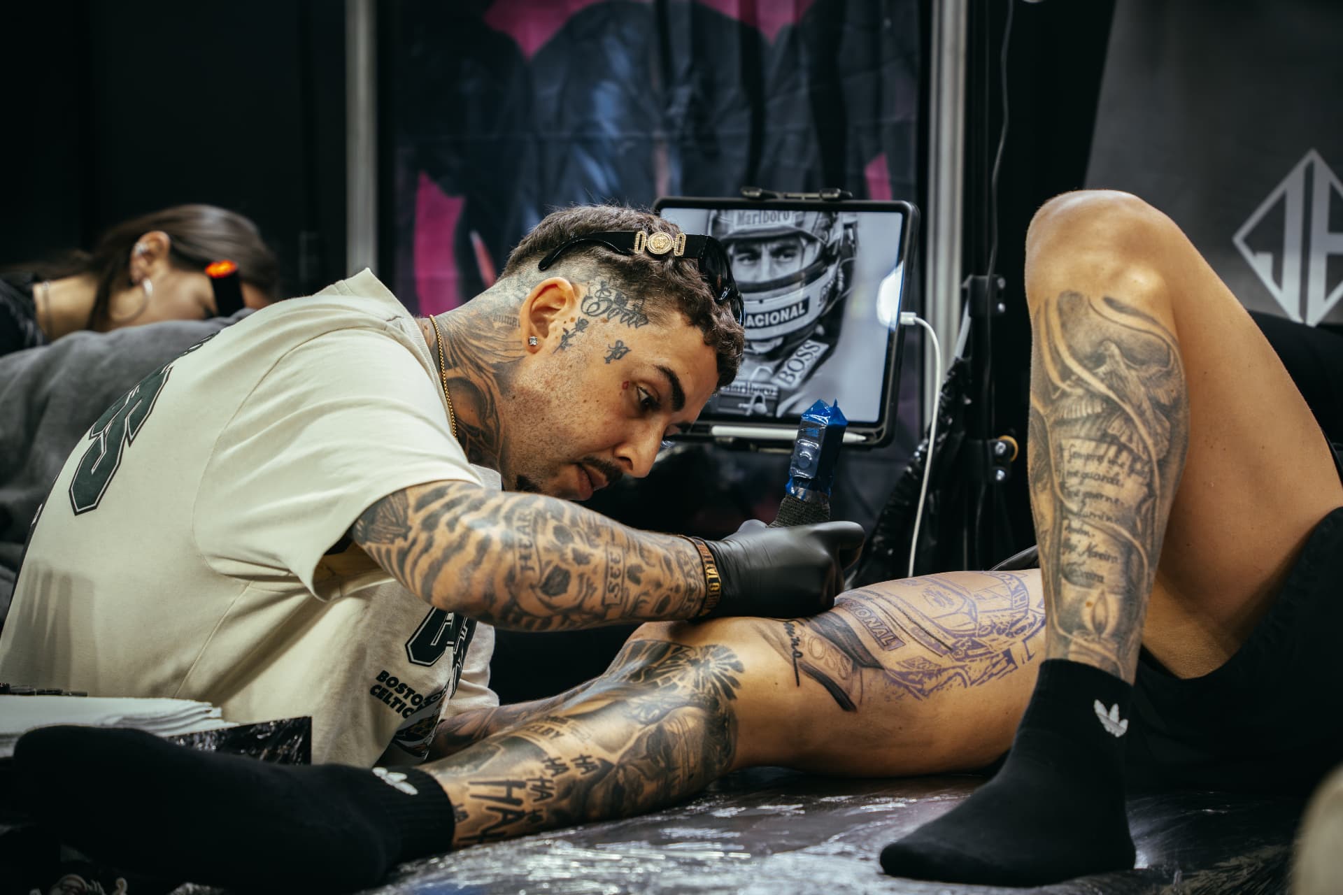 Tattoo artist working on a leg piece